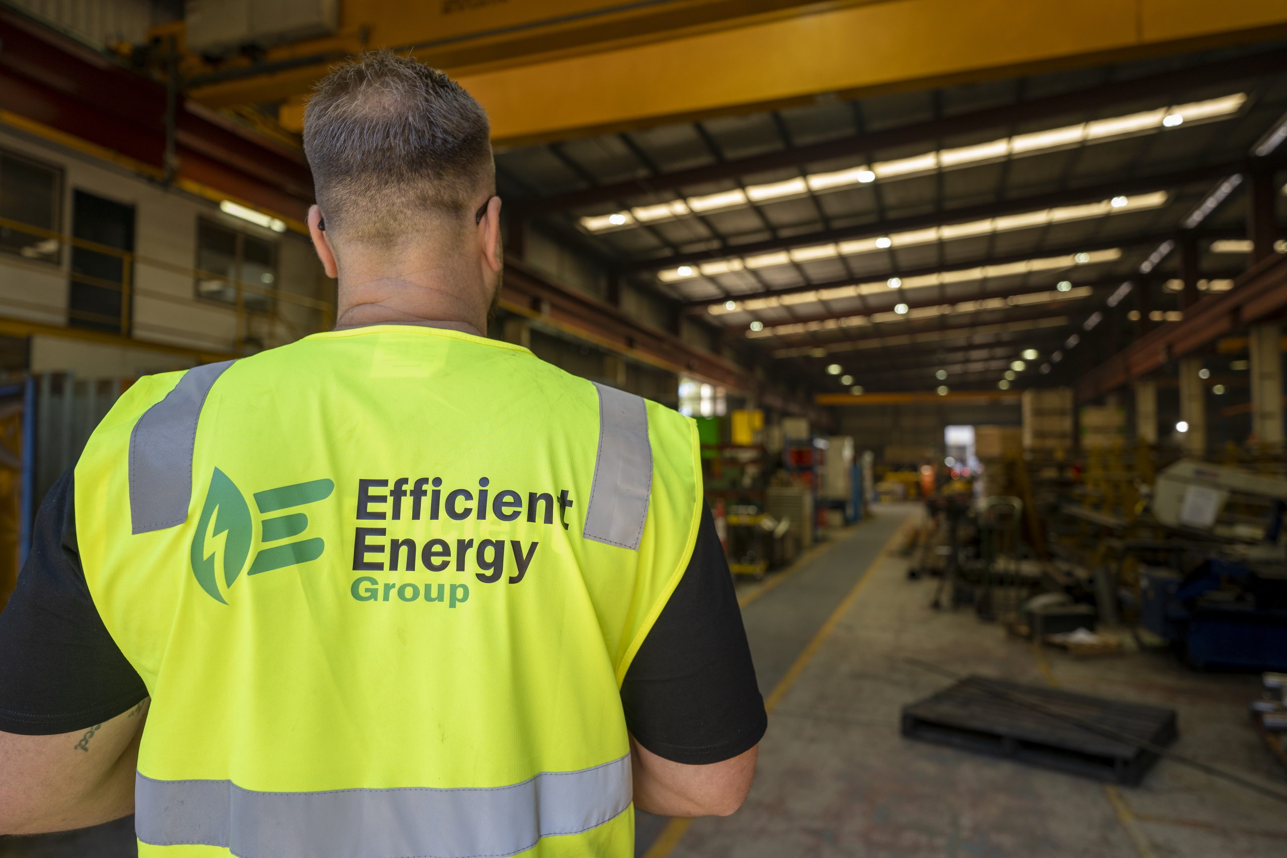 LED installer inside a warehouse in Queensland looking at high bays